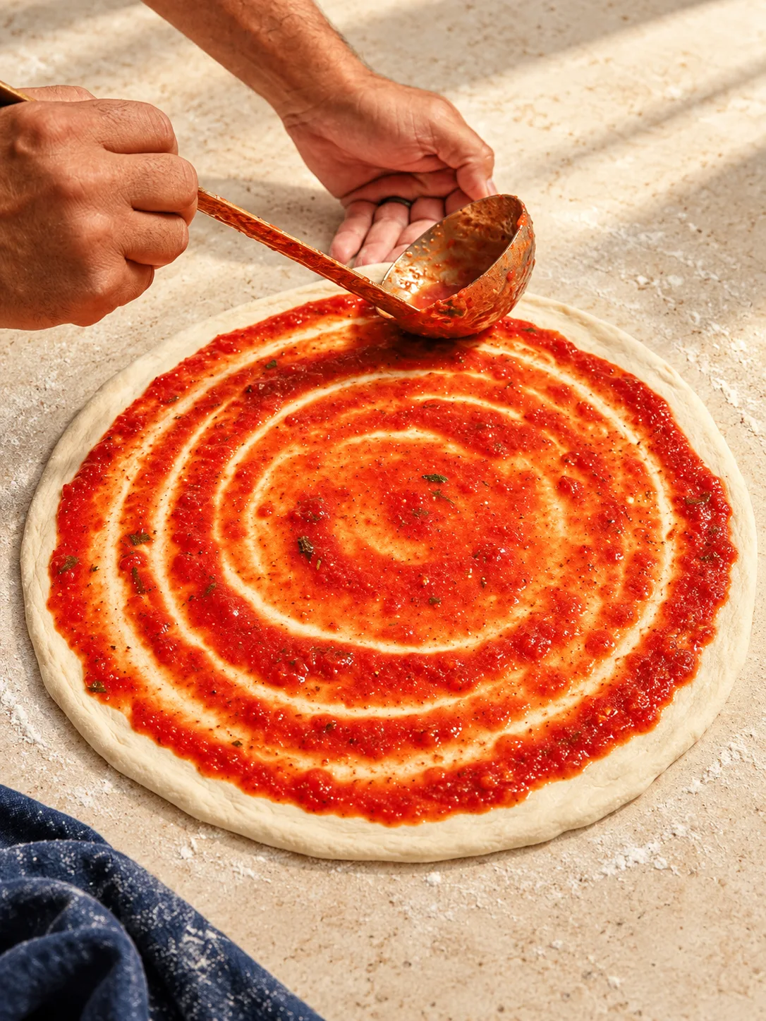 Home-made tomato sauce ladled onto dough